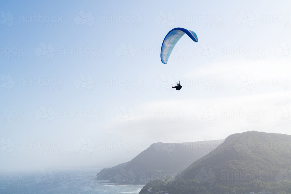 Paragliding against a brilliant sky and coastal mountain range - Australian Stock Image