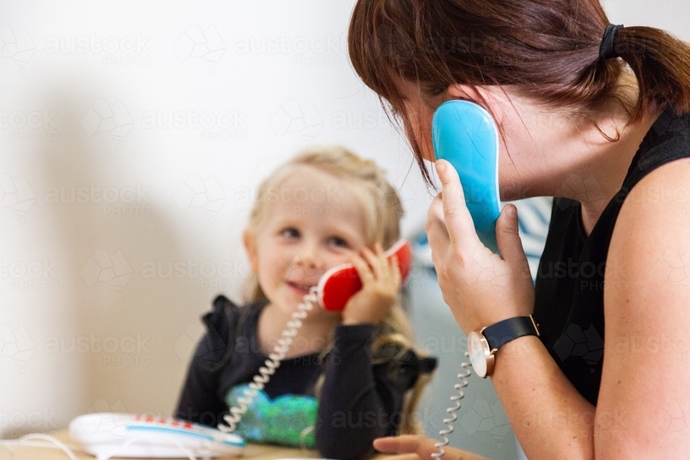 Parent and child talking together on toy telephone - Australian Stock Image