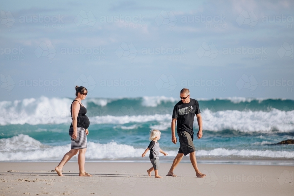 Parents and toddler walking on the beach, and the woman is pregnant - Australian Stock Image