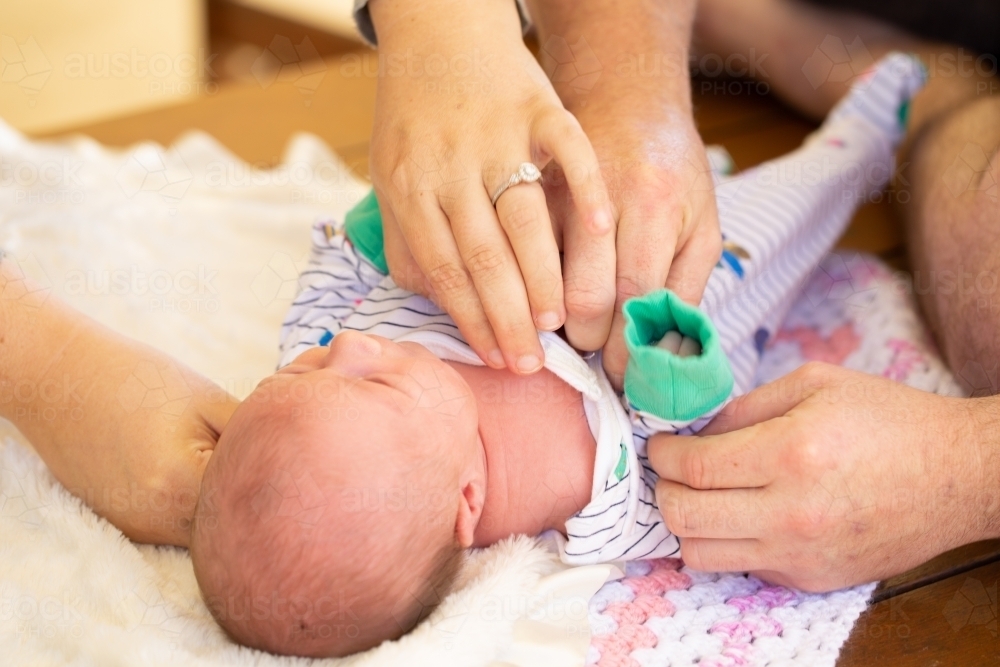 Parents dressing newborn baby - Australian Stock Image