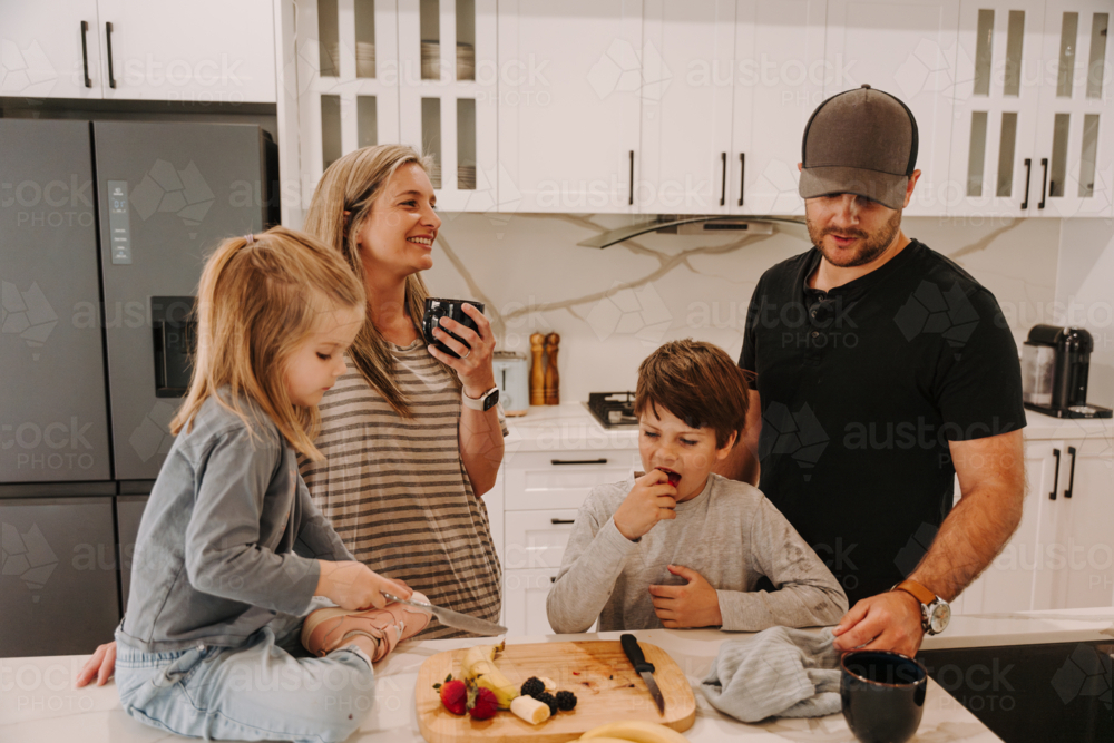 Parents teaching kids how to cut fruits in the kitchen. - Australian Stock Image