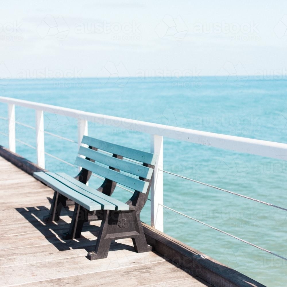 Park bench on a jetty overlooking ocean - Australian Stock Image