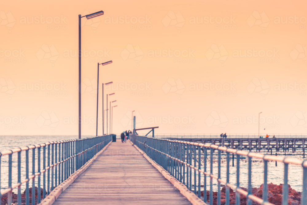 Partially defocused view of Moonta Bay jetty with people at dusk, Yorke Peninsula, South Australia - Australian Stock Image