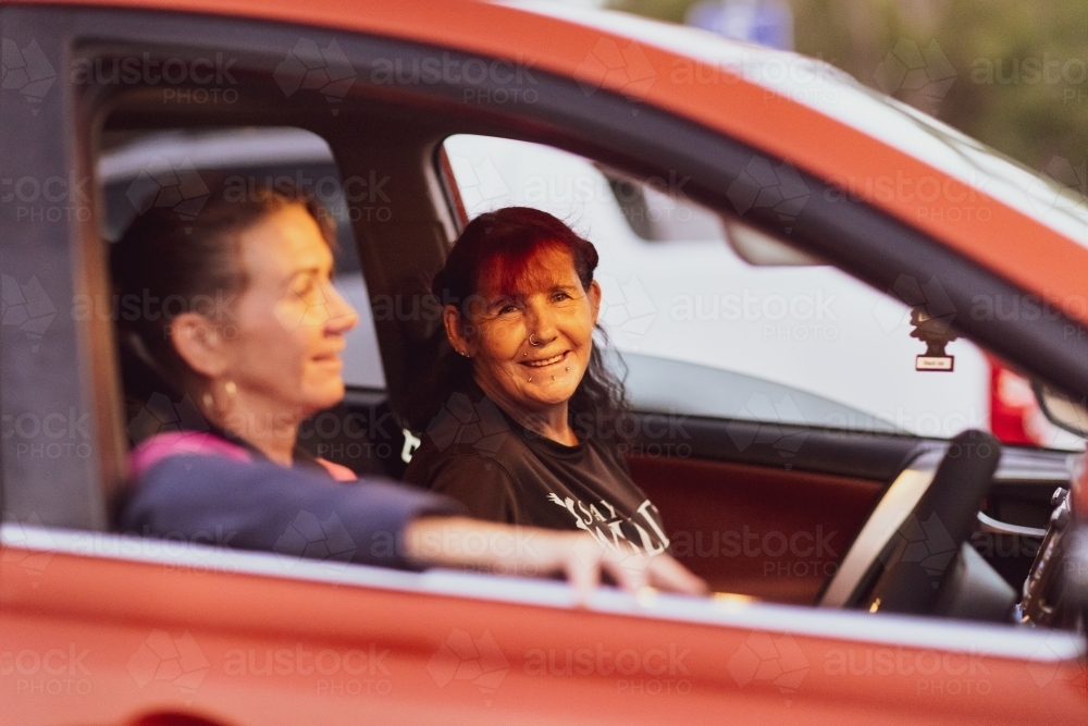 passenger in car looking at viewer with driver blurred in foreground - Australian Stock Image