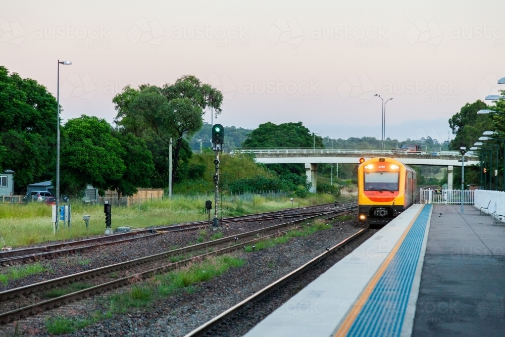 Passenger train coming into train station platform in the evening - Australian Stock Image