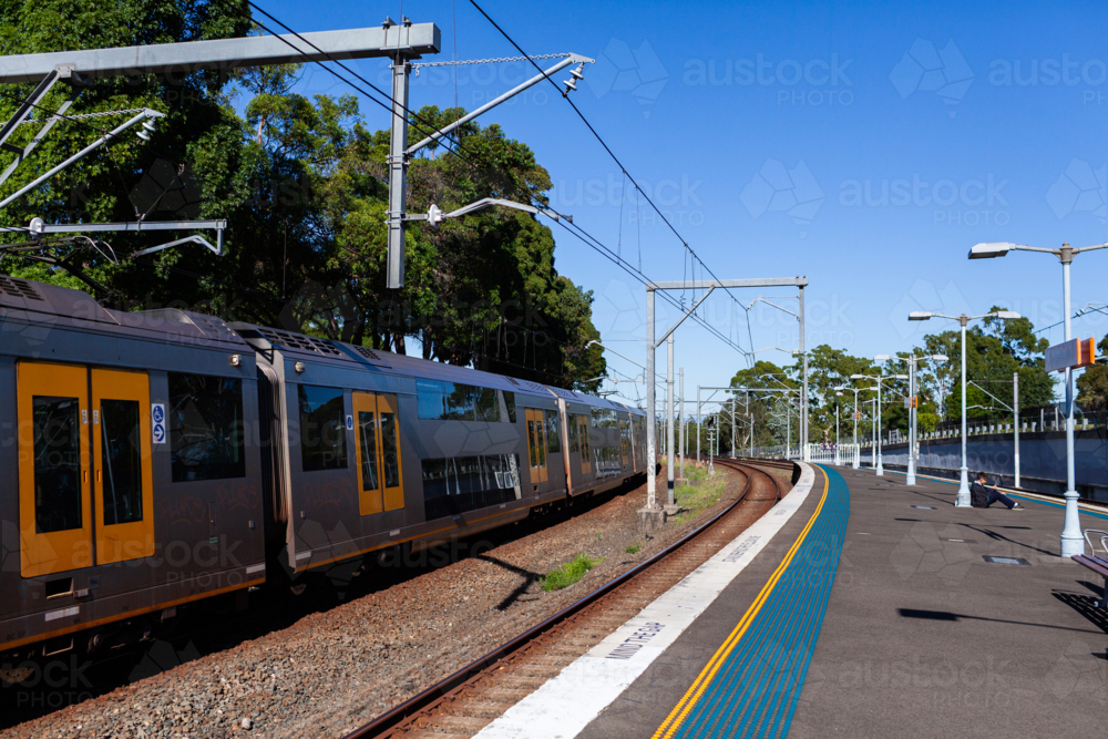 Passenger train passing platform of Narwee station in Sydney suburb - Australian Stock Image