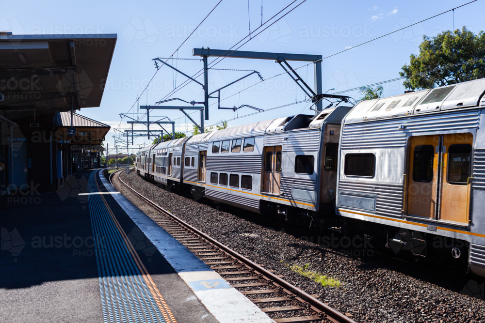 Passenger train passing platform of Narwee station in Sydney suburb - Australian Stock Image