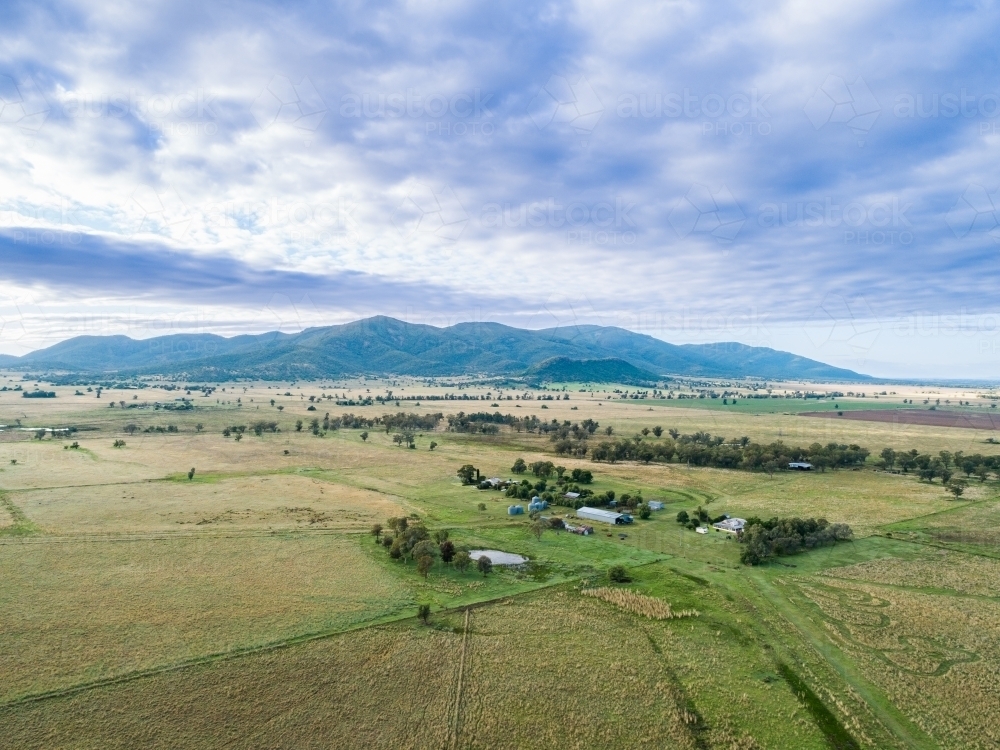 Pastel clouded sky above green farmland homestead in australian landscape - Australian Stock Image