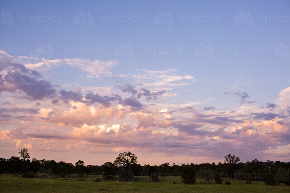 Pastel coloured sunset clouds above rural landscape - Australian Stock Image