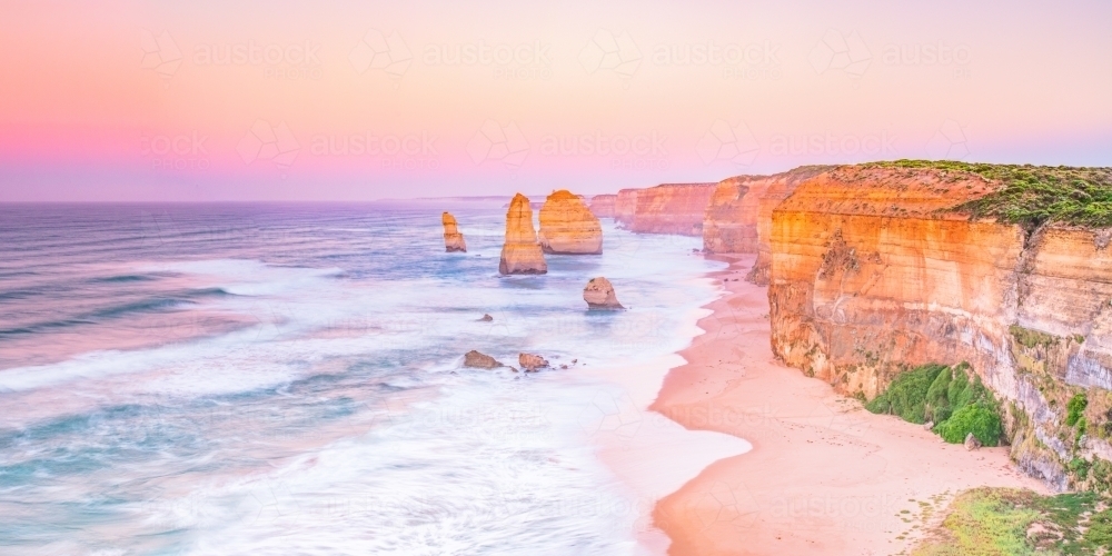 Pastel dawn colours at 12 apostles showing coastline - Australian Stock Image