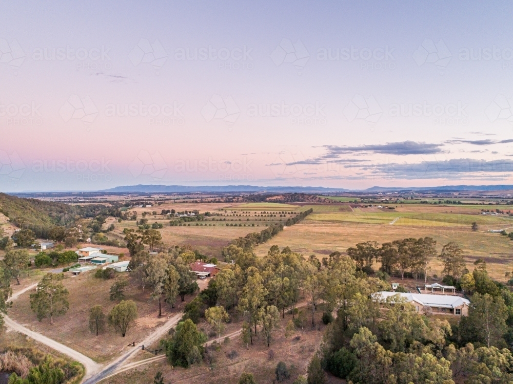 Pastel dusk sky over view of distant farm paddocks and cliff - Australian Stock Image