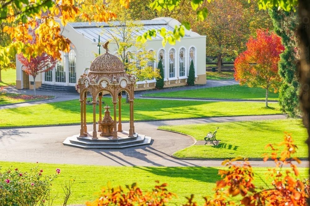 Paths leading to an ornate fountain near a conservatory in a city park - Australian Stock Image