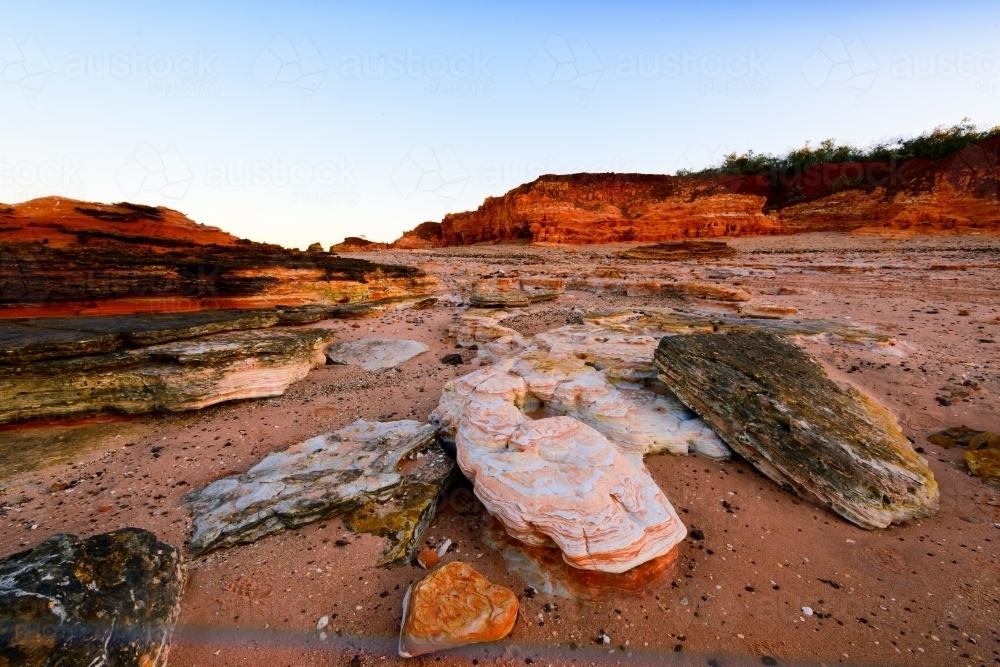 Patterned rocky beach bathed in pink sunset light - Australian Stock Image