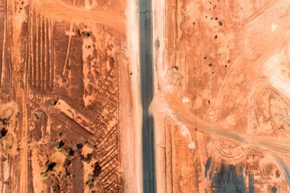 Patterns in red earth beside rural highway. - Australian Stock Image