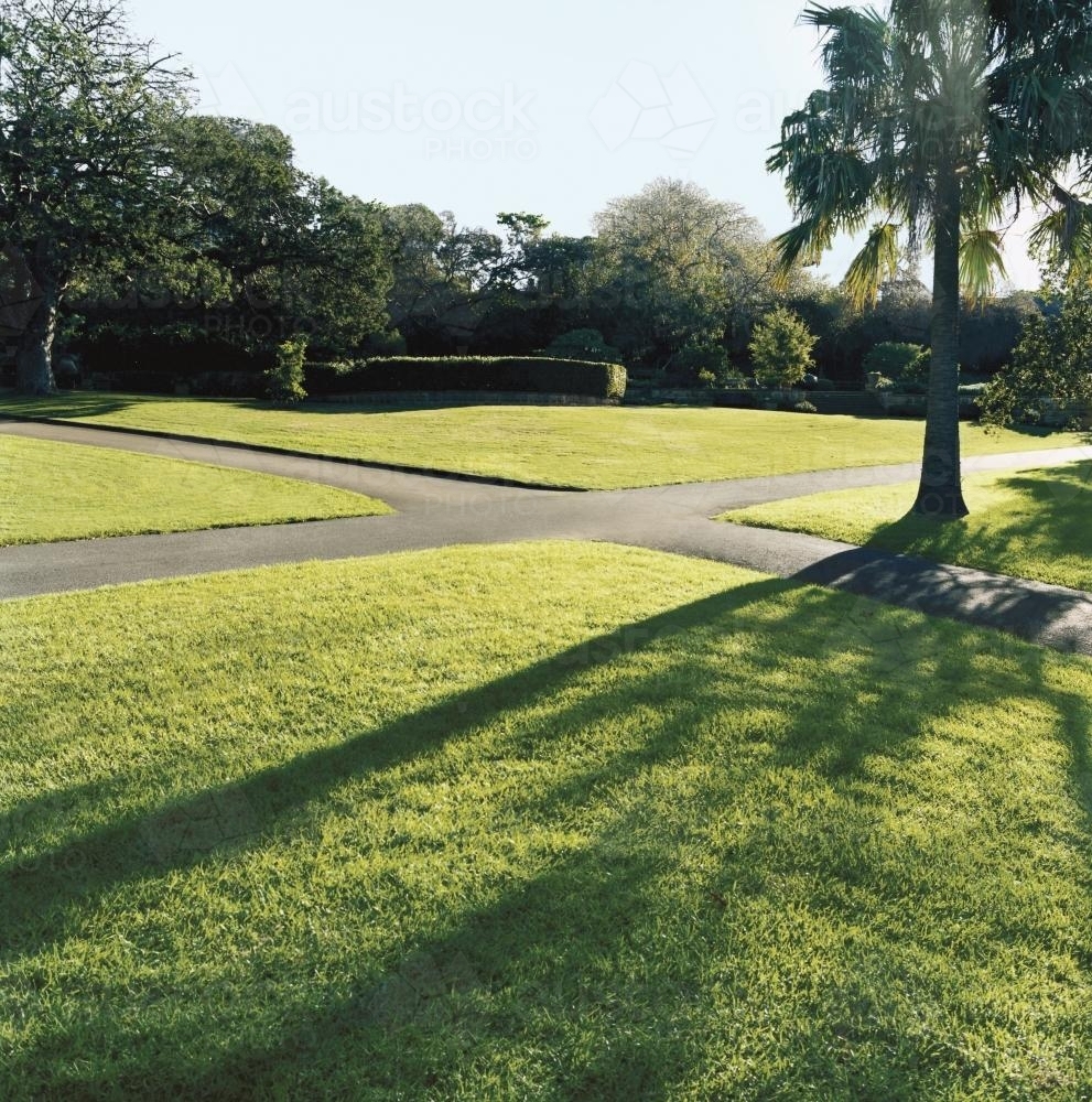 Paved pathways through parkland with light and shadow - Australian Stock Image