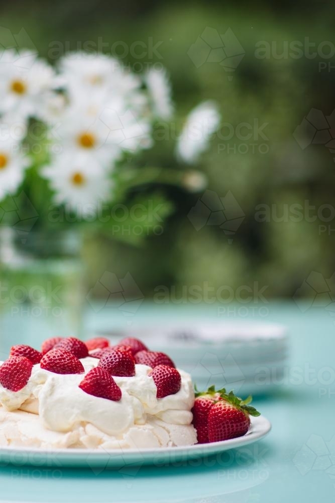 Pavlova topped with strawberries set out on a table outdoors in summer - Australian Stock Image
