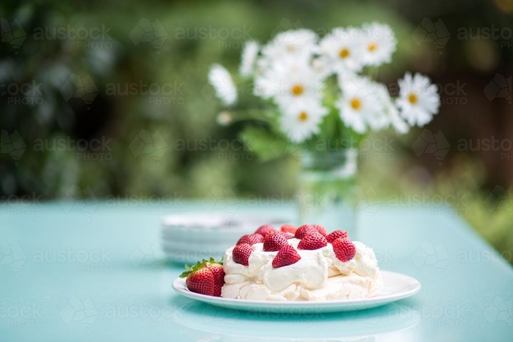 Pavlova with strawberries on an outdoor table in summer - Australian Stock Image