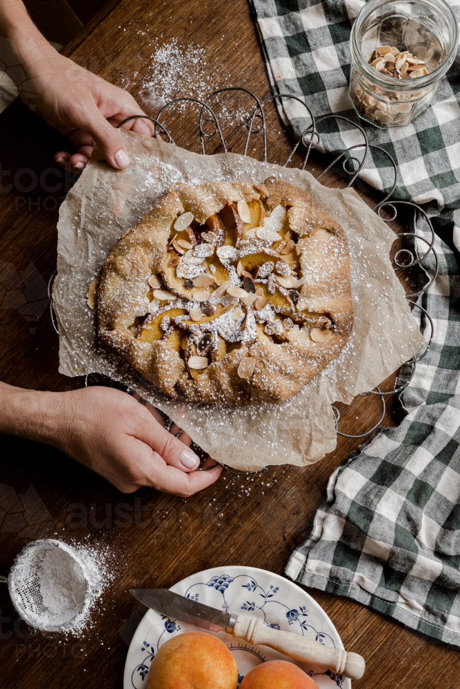 peach tart with hands on a timber tabletop : Austockphoto peach tart with hands on a timber tabletop - Australian Stock Image