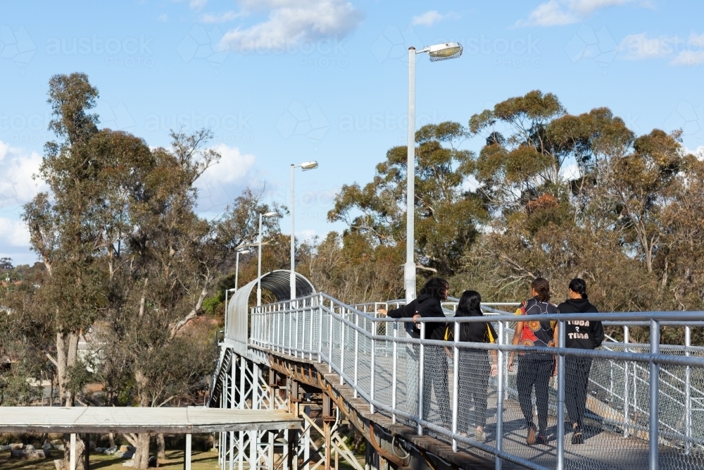 pedestrian bridge over railway line with young people crossing - Australian Stock Image