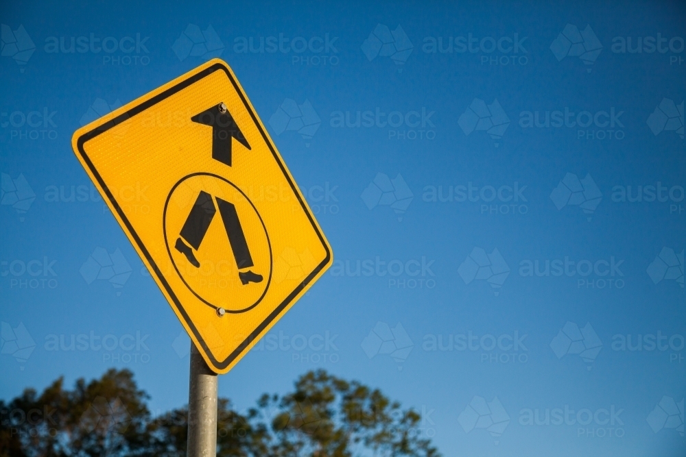 Pedestrians crossing ahead sign against blue sky - Australian Stock Image