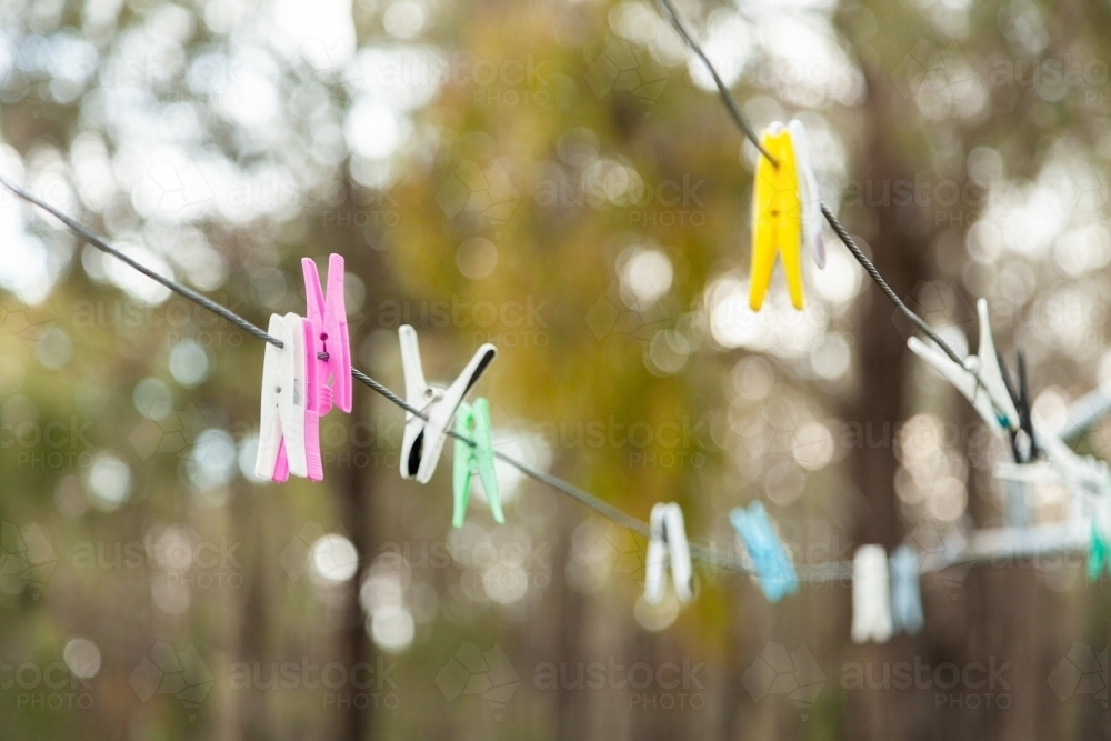 Pegs on clothesline on overcast day with bokeh light - Australian Stock Image