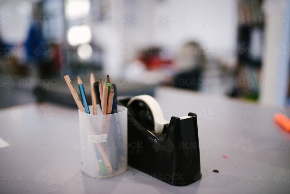 Pencils in a cup with a sticky tape holder on a desk - Australian Stock Image