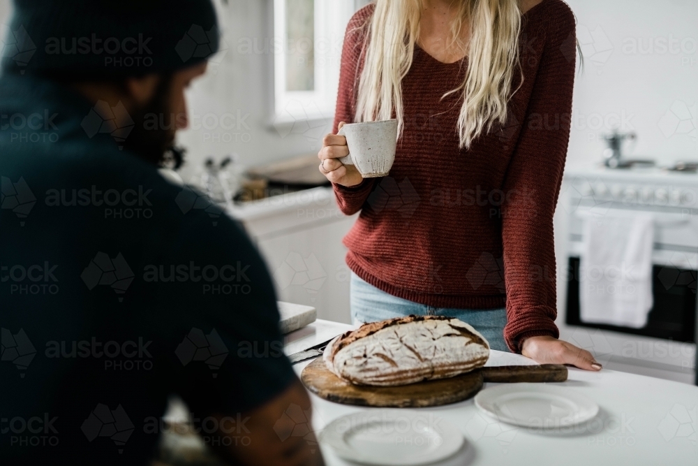 People at kitchen bench having a cup of coffee - Australian Stock Image