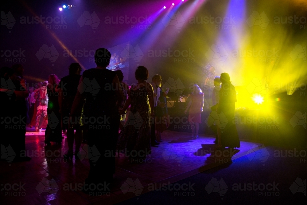 People dancing on dance floor at event with bright lights - Australian Stock Image