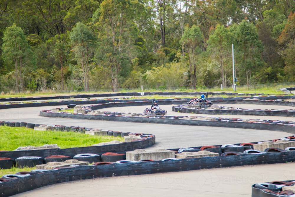 People driving go karts around outdoor track - Australian Stock Image