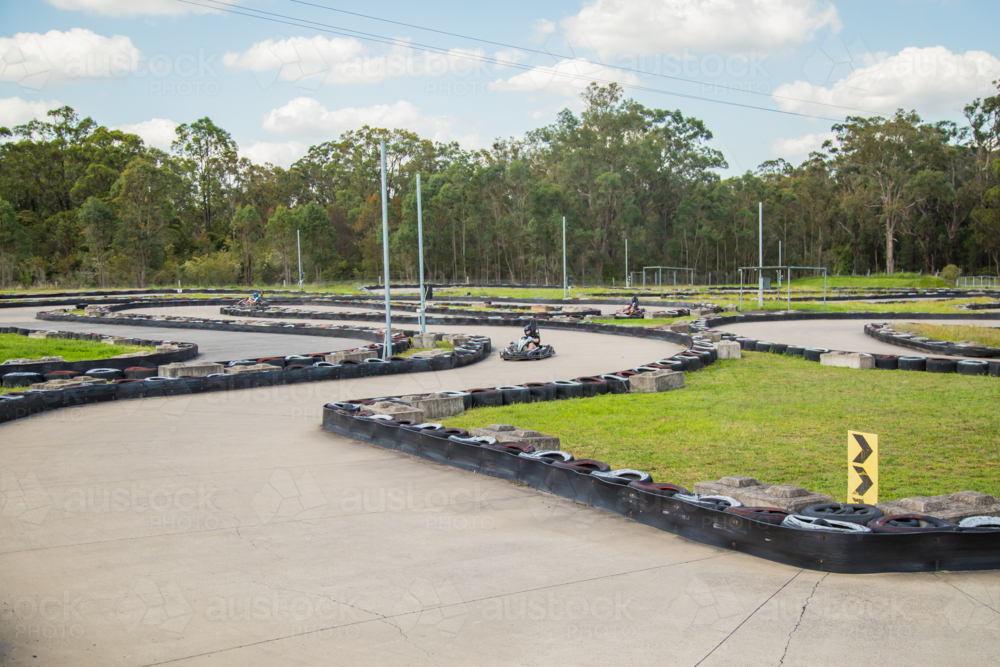 People driving go karts around outdoor track - Australian Stock Image