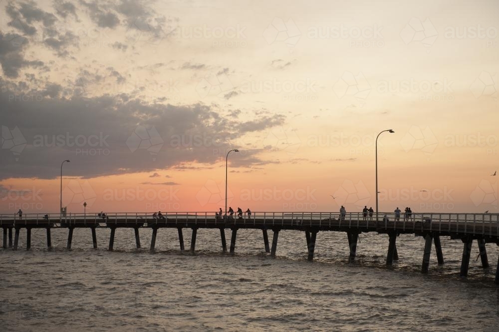 People fishing from Derby jetty at sunset - Australian Stock Image