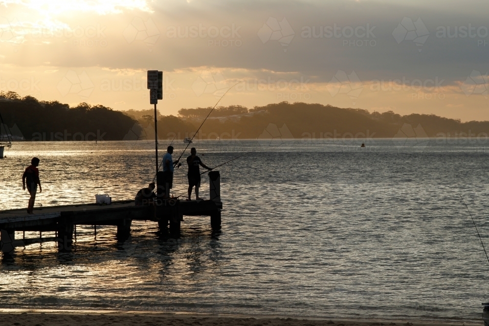 People fishing of a pier at dusk - Australian Stock Image