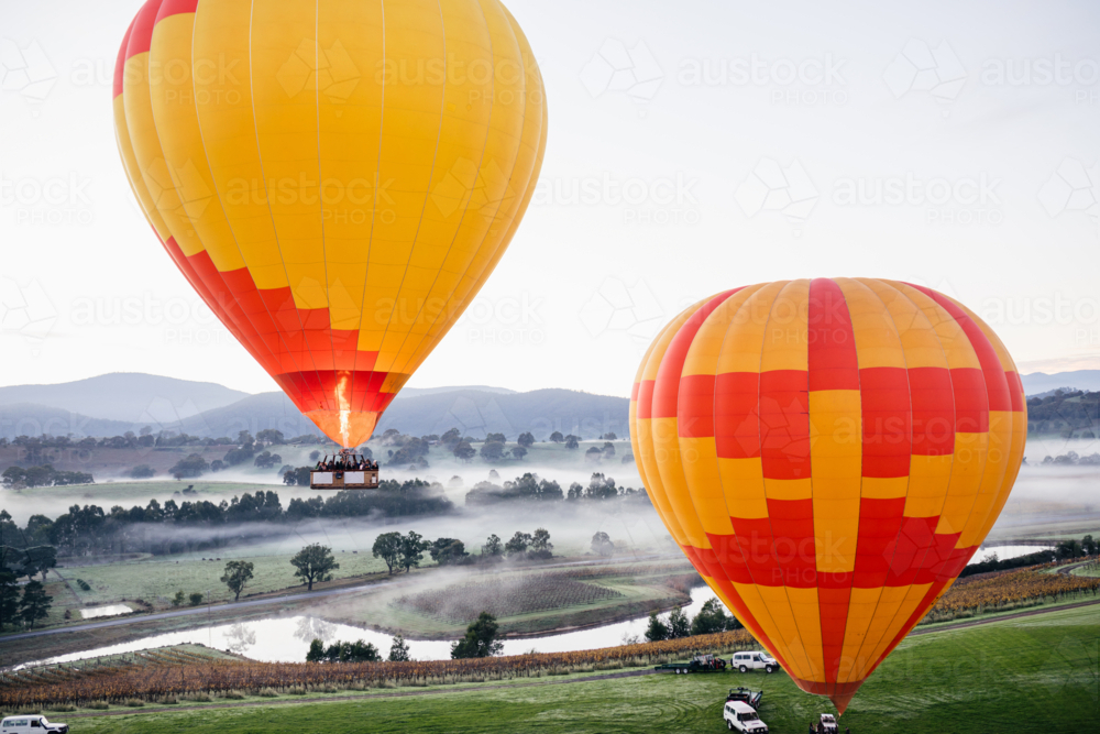 people Hot Air Ballooning in two orange and yellow balloons on cold morning - Australian Stock Image