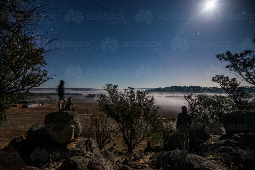 People looking out over paddock night time fog - Australian Stock Image