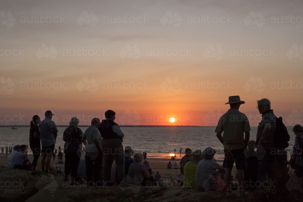 people on tropical beach at sunset - Australian Stock Image