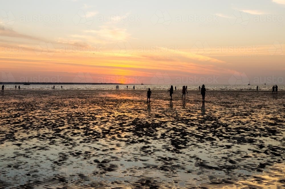 People out on the beach at low tide with setting sun - Australian Stock Image