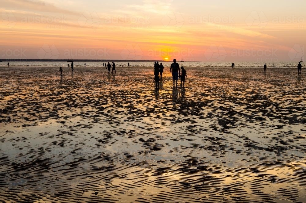 People silhouetted in the colourful sunset at Menindee Beach - Australian Stock Image