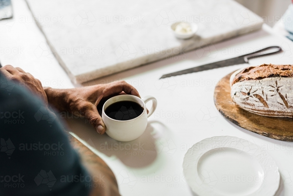 People sitting at a table drinking coffee and eating artisan bread - Australian Stock Image