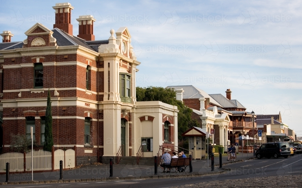 People sitting on bench in town with heritage buildings - Australian Stock Image
