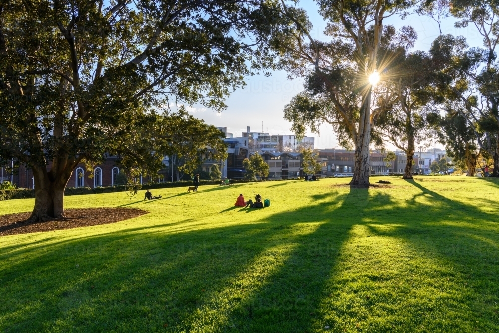 People sitting on lawn enjoy Sunday afternoon in a downtown park - Australian Stock Image