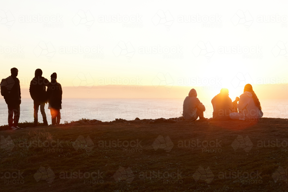 People standing by the beach at sunset - Australian Stock Image