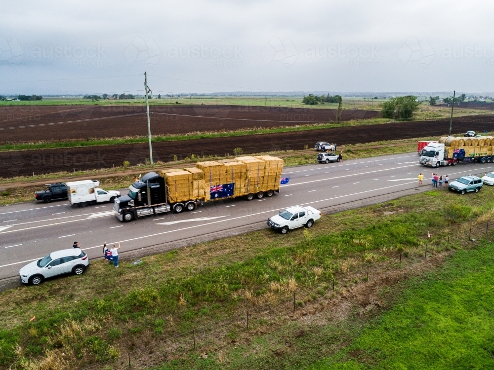 People stopped on highway waving to trucks as they deliver hay to farmers in drought - Australian Stock Image