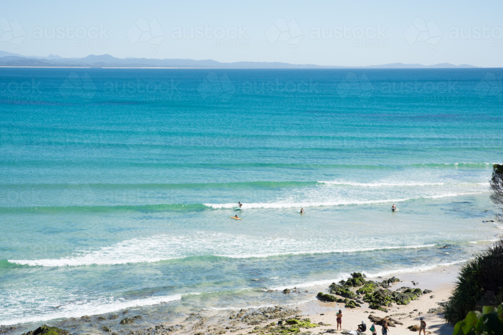 People swimming and surfing at the beach in Byron Bay - Australian Stock Image