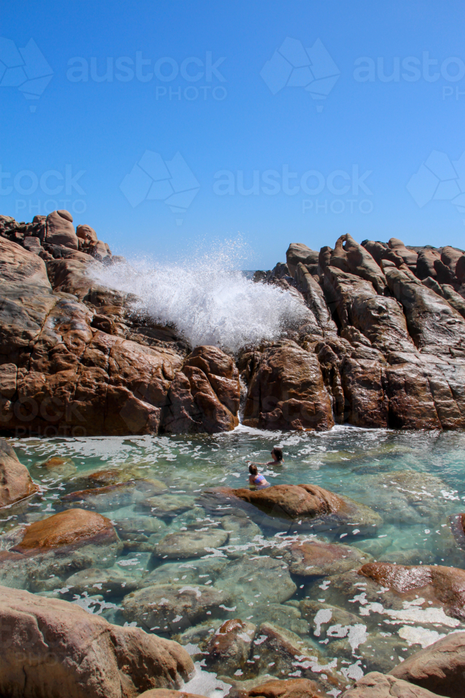 People swimming in natural ocean spa amongst rocks - Australian Stock Image