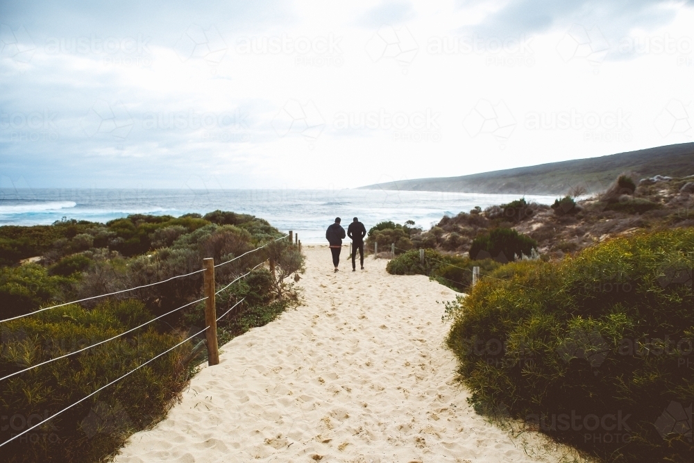 People walking at rugged beach - Australian Stock Image