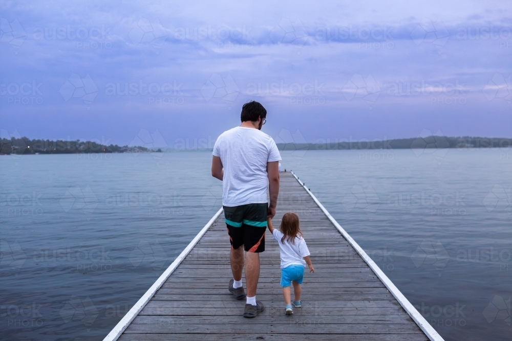 People walking down Warners Bay Public Jetty in dusk light - Australian Stock Image