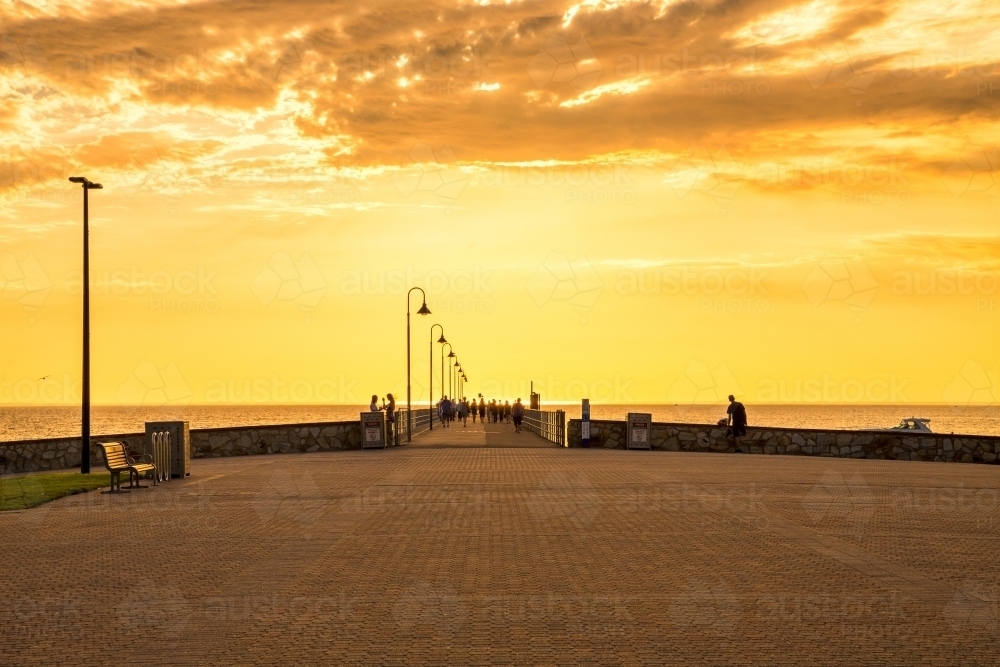 People walking on a jetty with a golden sunset - Australian Stock Image