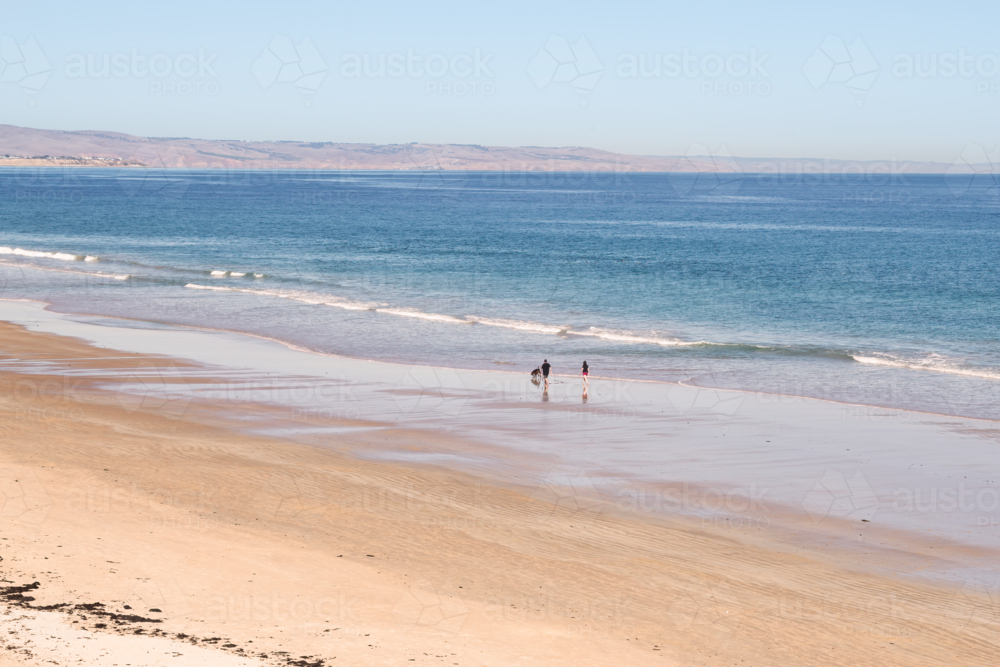 People walking on beach with their dog, Moana Beach, South Australia - Australian Stock Image