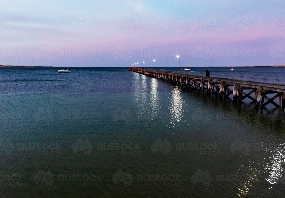 people walking on jetty in evening light - Australian Stock Image