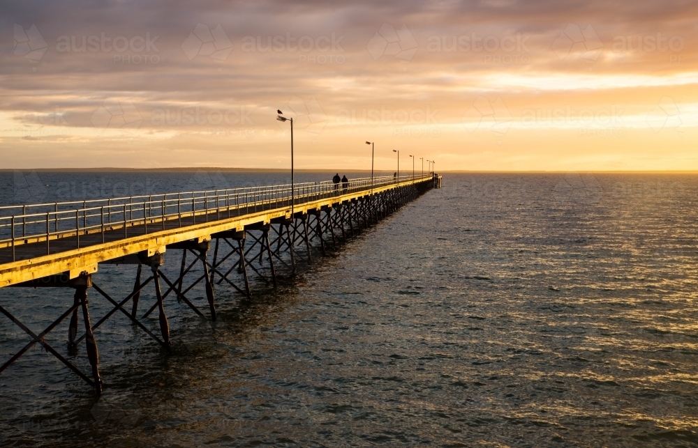 people walking on jetty in late afternoon light - Australian Stock Image